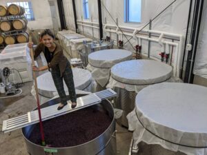 Karla Punching down the cap in a fermenter.